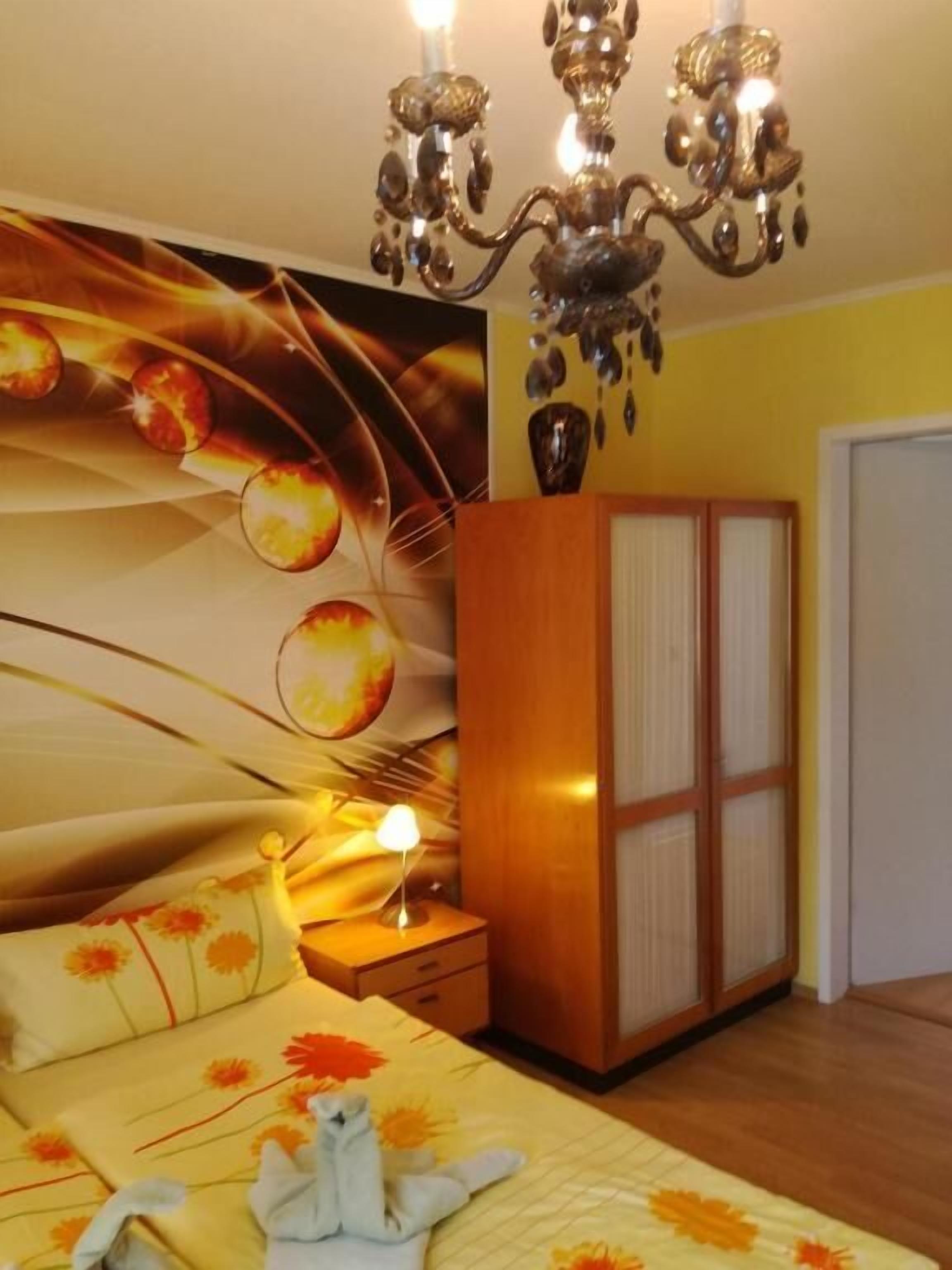 Une chambre à coucher comprenant un lit, une table de chevet, une armoire et un lustre.