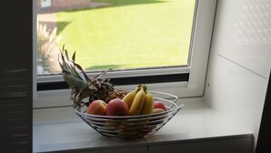 Uma janela da cozinha com uma fruteira no parapeito.