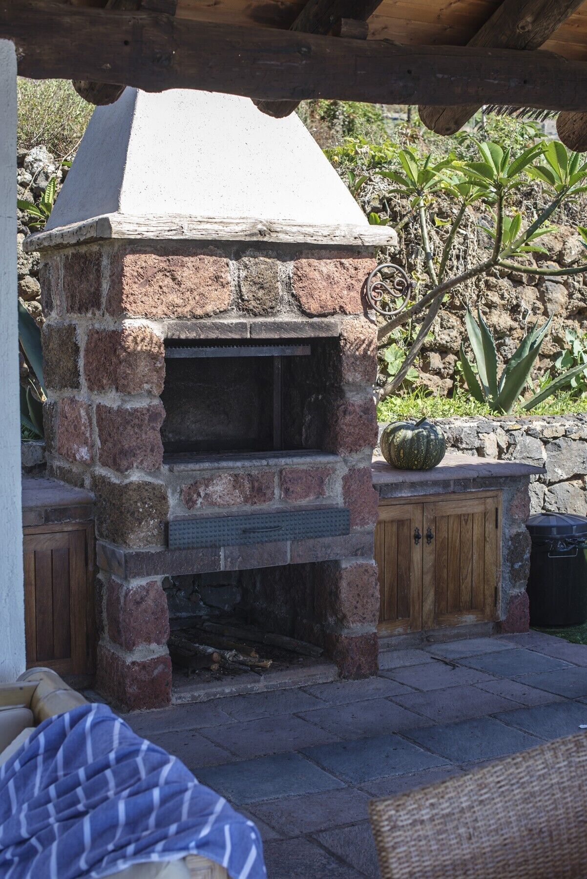 Ein Outdoor-Backofen aus Ziegelsteinen mit einem Steinkamin, einem Holzschrank und einem Blumentopf.