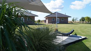 Ein Haus mit Backsteinfassade, einem Rasen und einer großen weißen Markise.