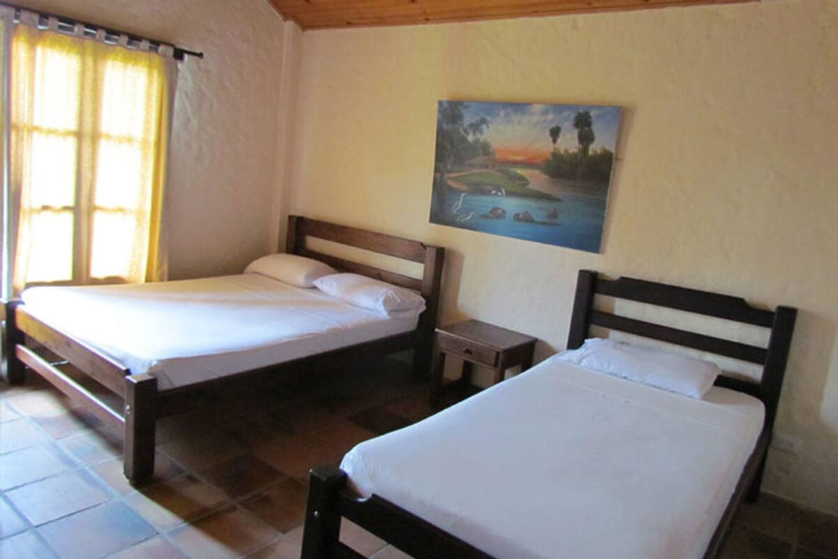A room with two single beds, a small bedside table, and a painting on the wall.