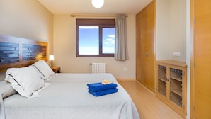 Una camera d'albergo con un letto, un comodino, una finestra con tende, un termosifone e un armadio.