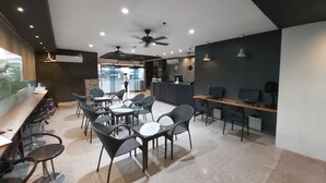 A modern office space with a reception area, several tables and chairs, and a ceiling fan. - DG Grami Hotel (Parañaque)