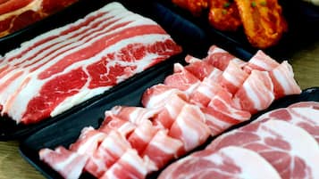 A variety of raw meats, including different cuts of pork and beef, displayed on trays.