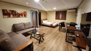 A modern living room with a sofa, a coffee table, a bed, and a dining area. - DG Grami Hotel (Parañaque)