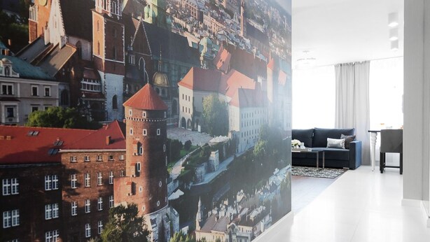 Een moderne hotelkamer met een grote stadsmuurschildering, een witte betegelde vloer, een donkerblauwe bank en een kleine tafel.