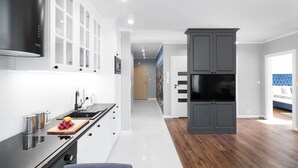 Een moderne keuken met een zwarte afzuigkap, witte kasten en een houten vloer.