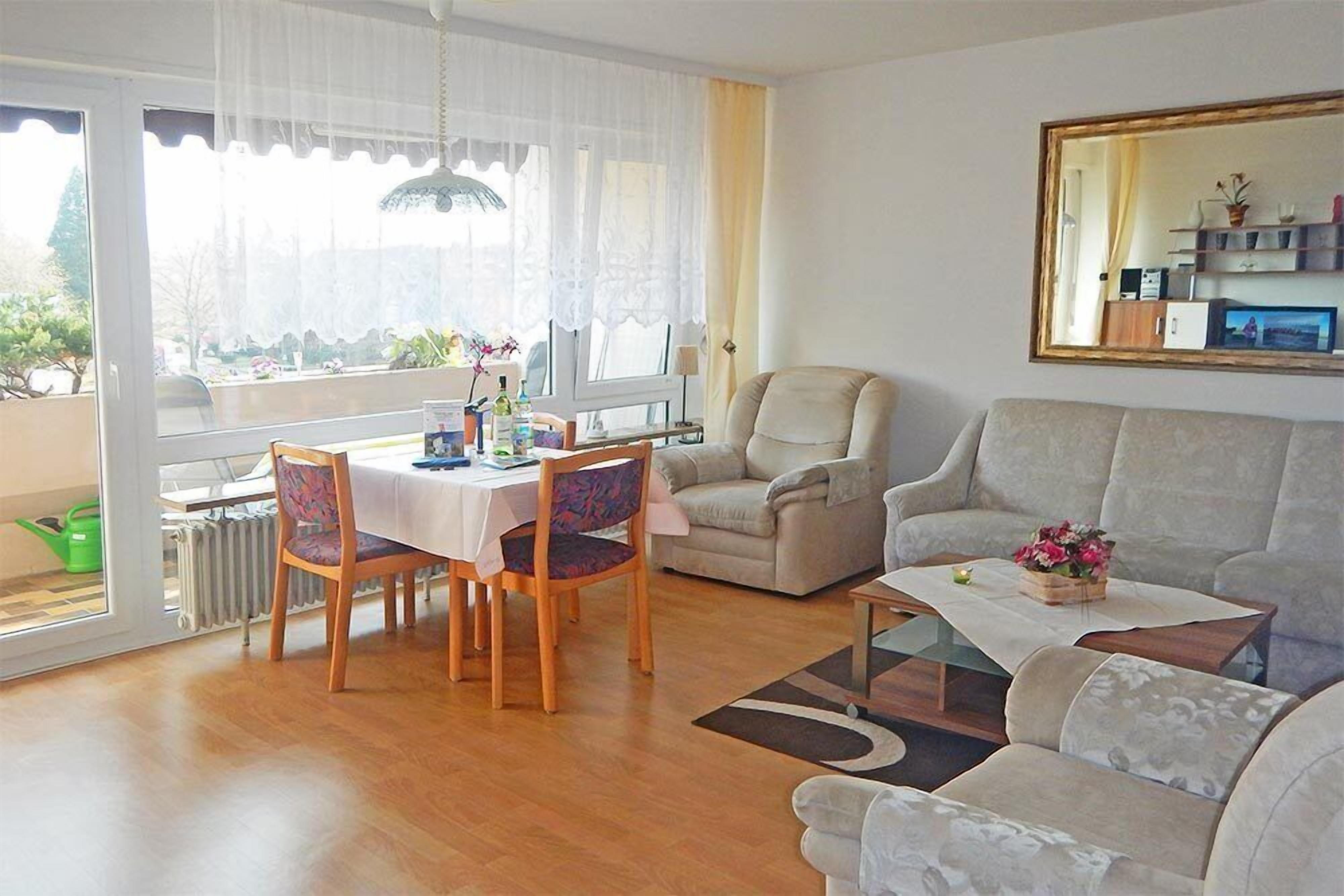 Una sala de estar con comedor, un sofá, una mesa de centro y un ventanal con cortinas.