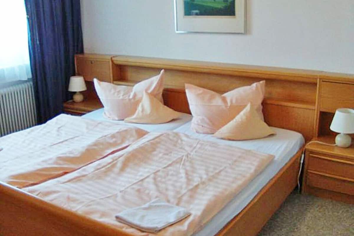 A double bed with a wooden headboard, two bedside tables with lamps, and a framed picture on the wall.