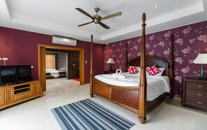 A four-poster bed with a wooden frame, a television on a wooden cabinet, and a bathroom visible through an open door. - Stunning Luxury Golf and Pool Villas (Pattaya)