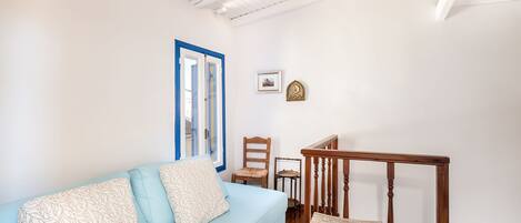 Une pièce avec un canapé bleu clair, une chaise en bois, une petite table et une rambarde en bois.
