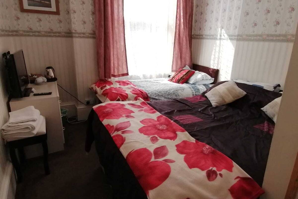A hotel room with two beds, a desk with a mirror, and a small table with towels.