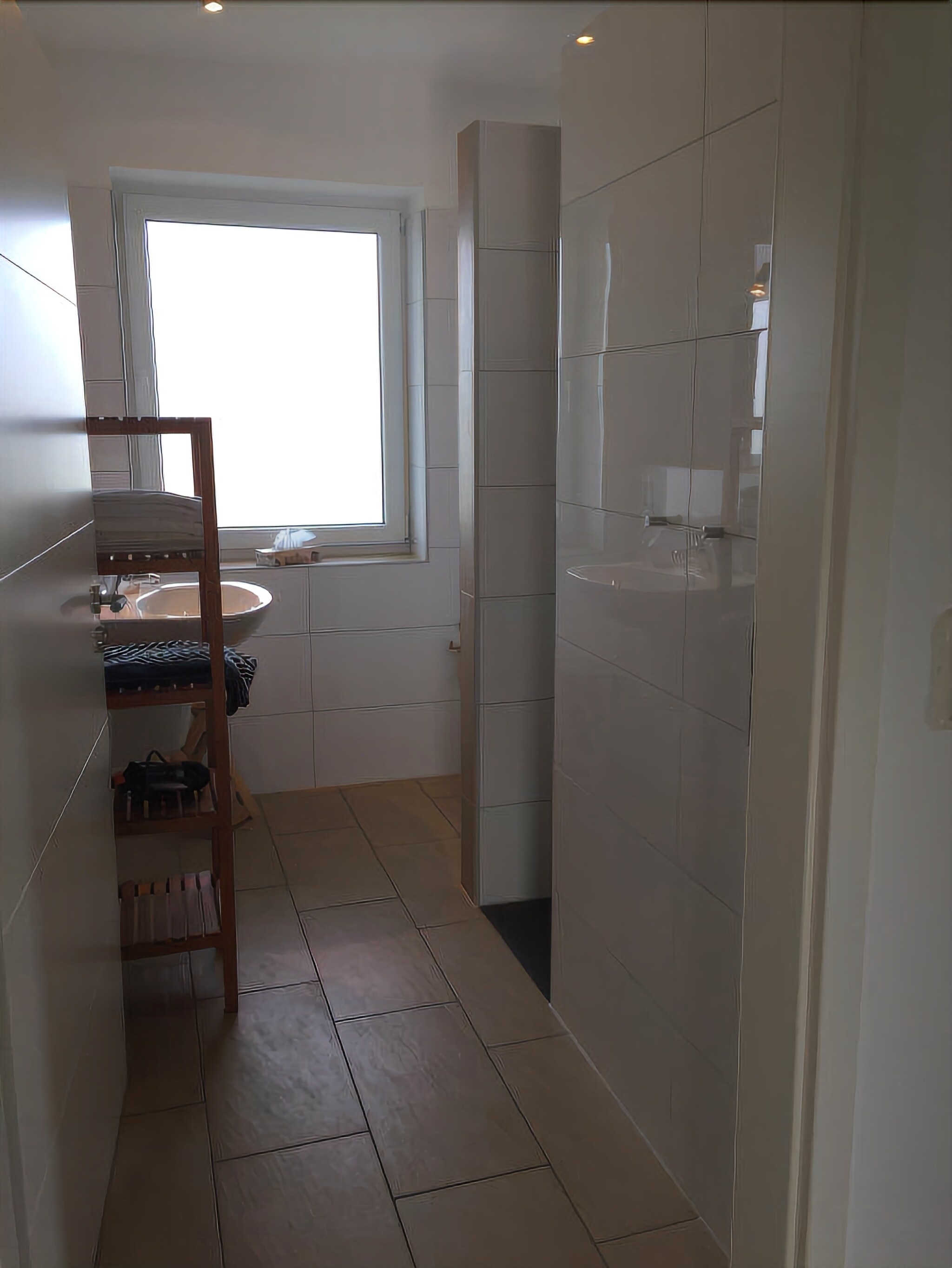 Une salle de bain avec une fenêtre, un lavabo et un espace douche.
