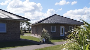 Two brick houses with tiled roofs, a paved driveway, and a grassy lawn. - Strandleben Fehmarn - Ferienhaus 3 (Fehmarn)