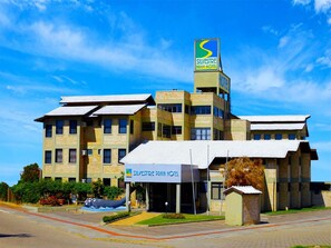 Un hotel con un llamativo letrero que dice 'Silvestre Praia Hotel', varios pisos y un estacionamiento.