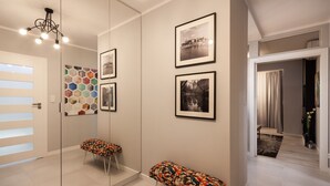 Un pasillo moderno con un panel de vidrio, fotografías en blanco y negro enmarcadas, y una llamativa obra de arte hexagonal en la pared.