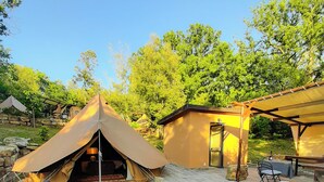 A tented camping area with a small building, a table with chairs, and a bench. - Serraiola Alta (Monterotondo Marittimo)