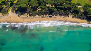 An aerial view of a beach with clear turquoise waters, a sandy shore, and dense green foliage in the background. - Serraiola Alta (Monterotondo Marittimo)