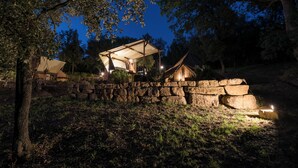 A stone wall with a covered area, possibly a patio or lounge, surrounded by trees. - Serraiola Alta (Monterotondo Marittimo)