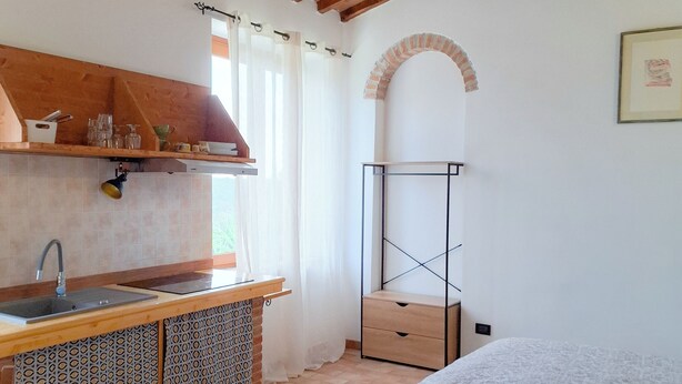 A compact room with a kitchenette, a bed, and a small table.