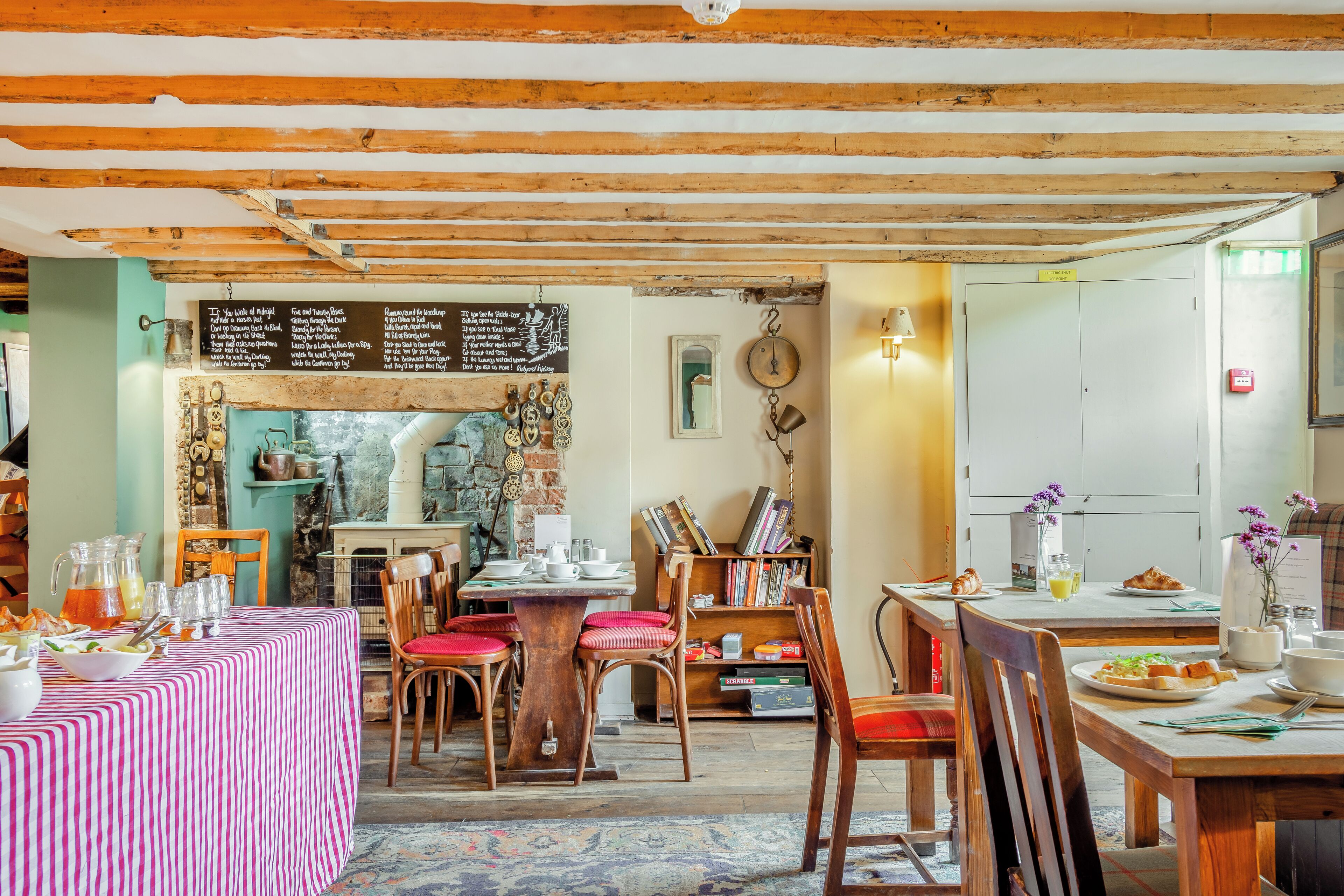 Un comedor acogedor con vigas de madera, un menú en pizarra y diferentes opciones de asiento.
