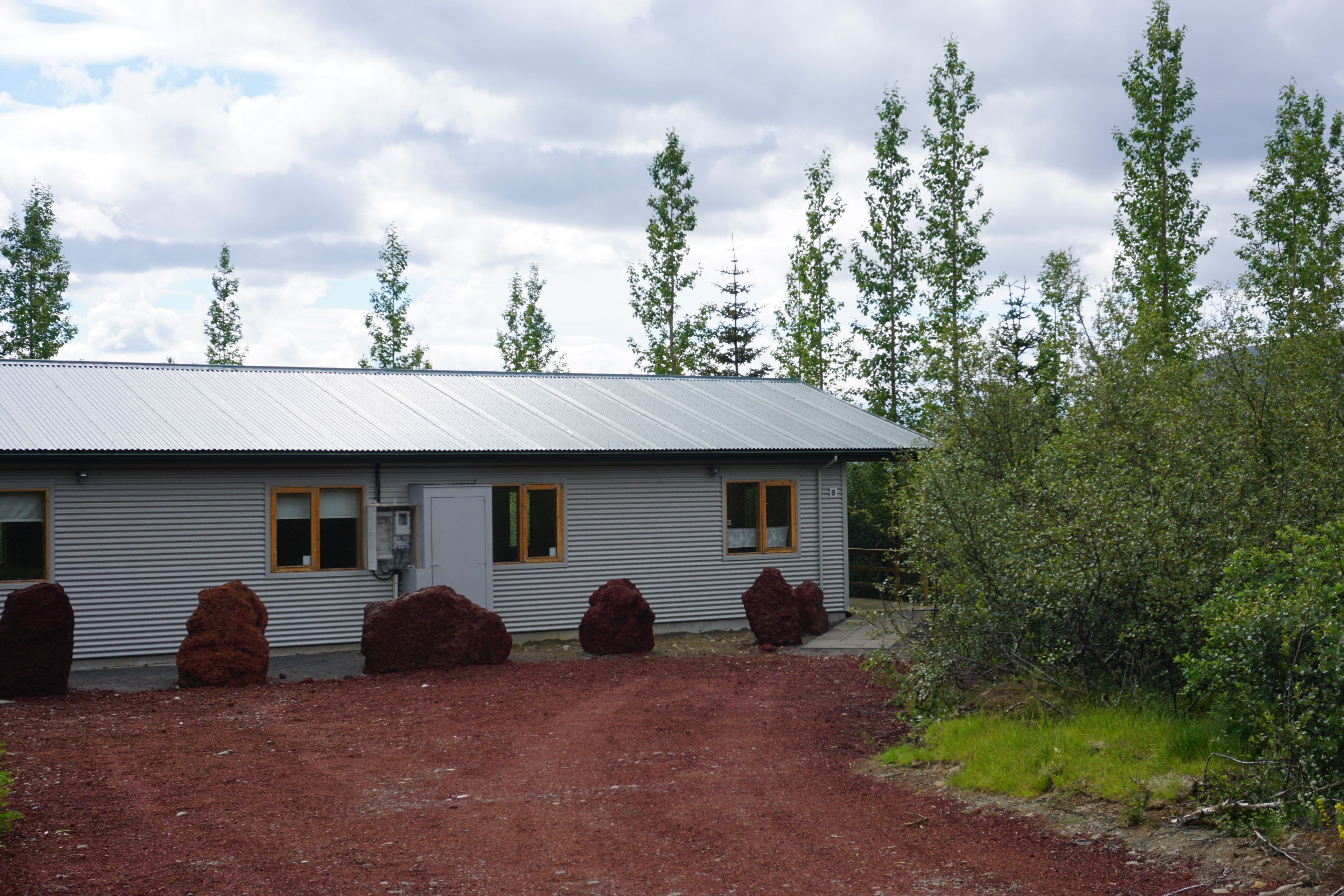A single-story building with a metal roof and a gravel driveway.