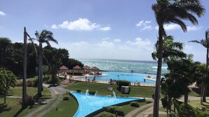 A resort with a large pool, palm trees, and a view of the ocean.