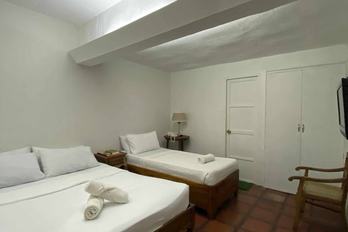 Ett hotellrum med två sängar, en trästol, ett nattduksbord med en lampa och en garderob.