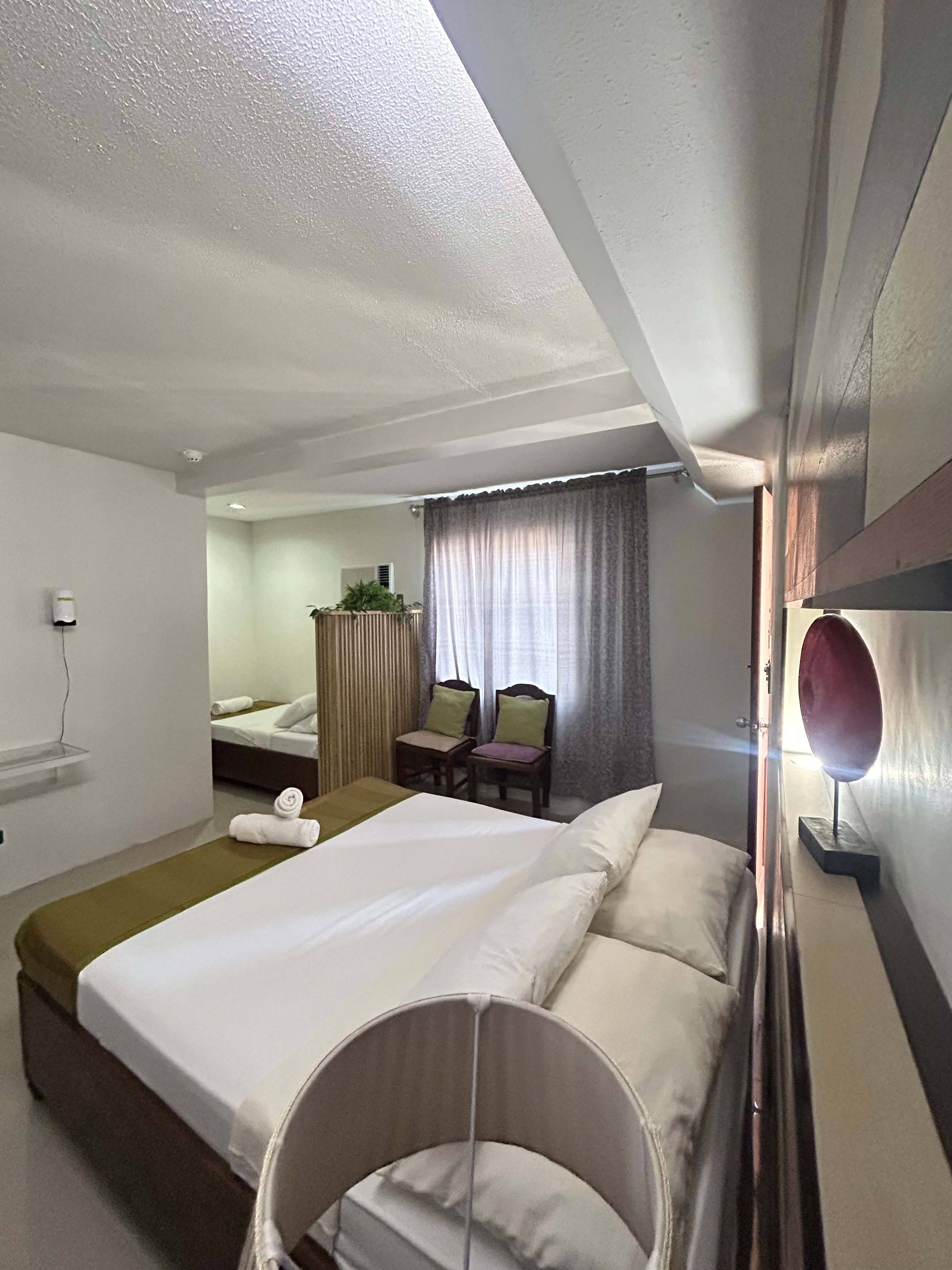 Ein Hotelzimmer mit Bett, Stuhl, kleinem Tisch und Spiegel.