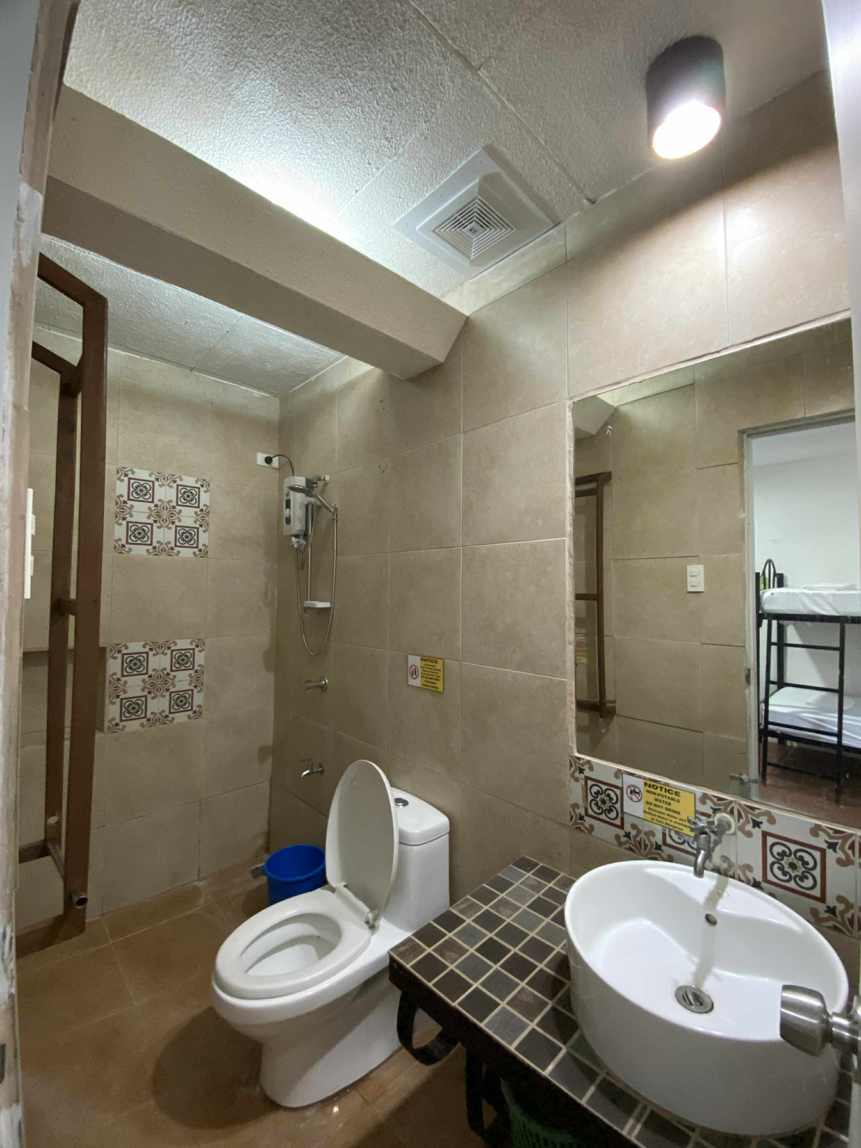 Un baño con inodoro, lavamanos, ducha y paredes de azulejos.