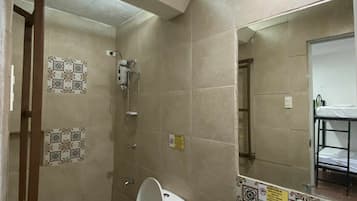 Un baño con inodoro, lavamanos, ducha y paredes de azulejos.