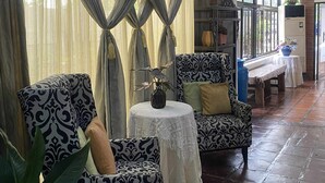 Un espace intérieur spacieux, agrémenté de fauteuils à motifs, d’une petite table ronde avec un vase et d’un banc.