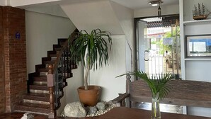 Un escalier orné d’un pot de fleurs, un banc en bois et un ventilateur au plafond.