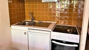 Une cuisine de taille réduite, dotée d’un évier encastré, d’un lave-vaisselle et d’une cuisinière.