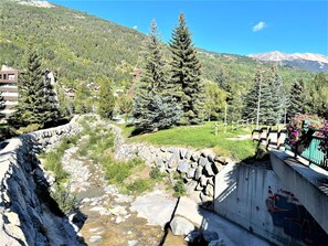 Une rivière traverse une vallée, bordée d’un côté par un mur de pierre et de l’autre par une clôture en bois.