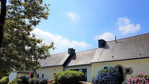 A two-story house with a sloped roof, a chimney, and a small porch with steps leading to the entrance.