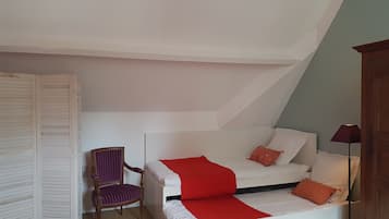 Una camera da letto con un letto bianco, una coperta rossa e una sedia viola.