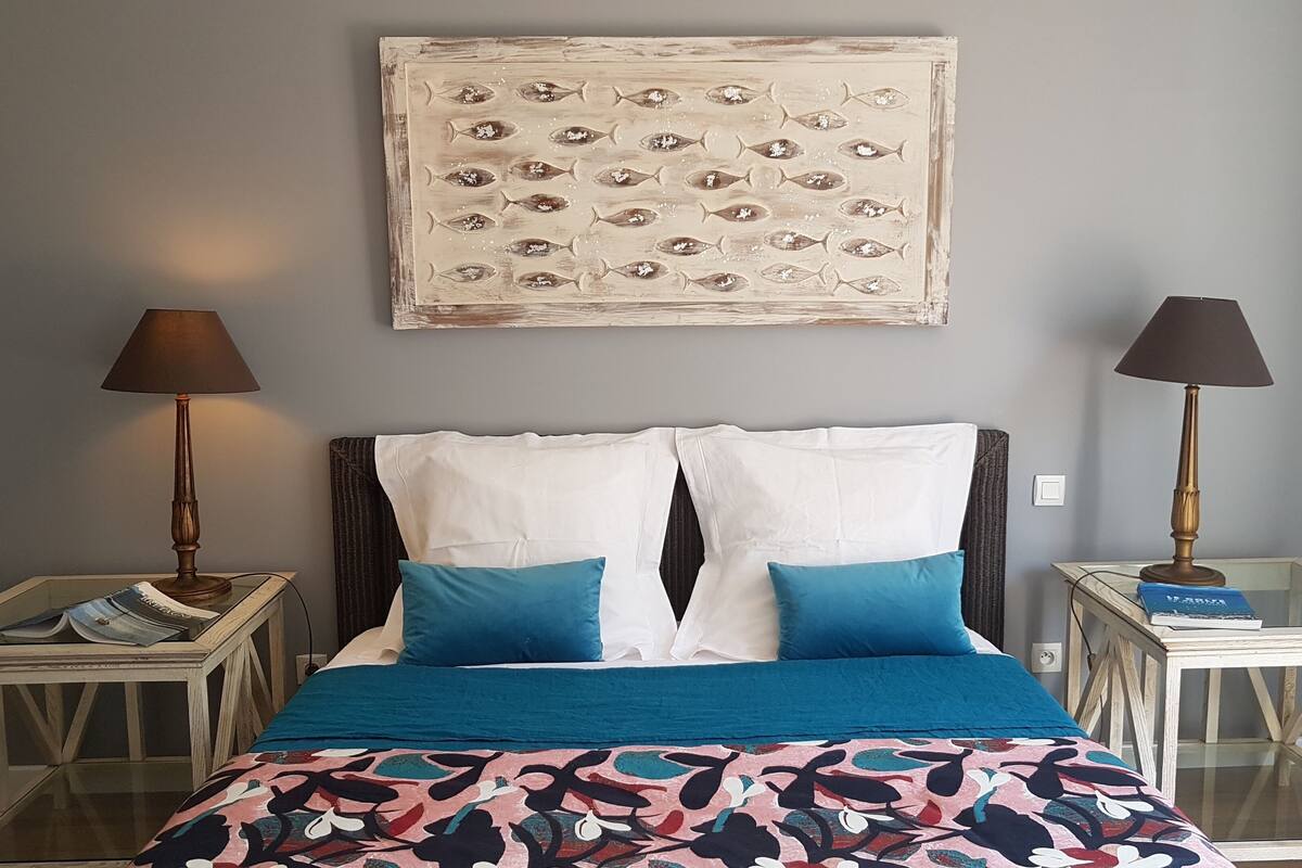 A bedroom with a bed, two bedside tables, lamps, and a wall art piece.