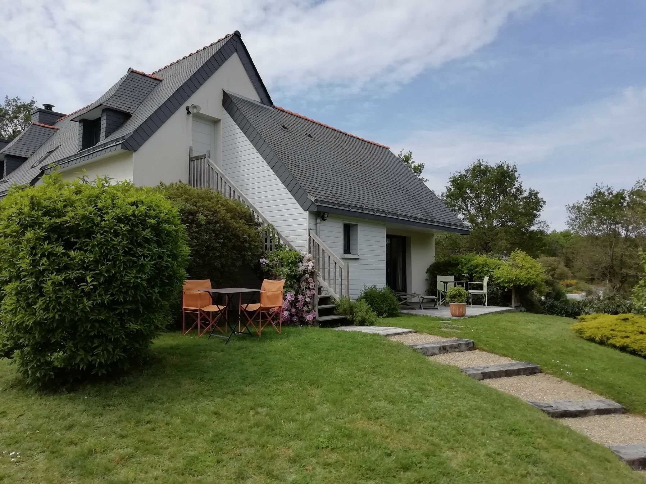 A two-story house with a sloped roof, a small porch, and a well-maintained lawn.