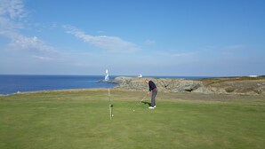 A golf course with a lighthouse in the background.