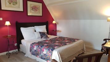A bedroom with a bed, two bedside tables, a nightstand, a chair, and a red accent wall.