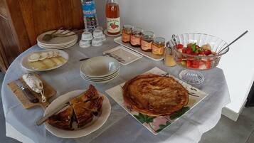 Una mesa con varios platos, incluyendo queso en rodajas, una quiche y una ensalada de frutas.