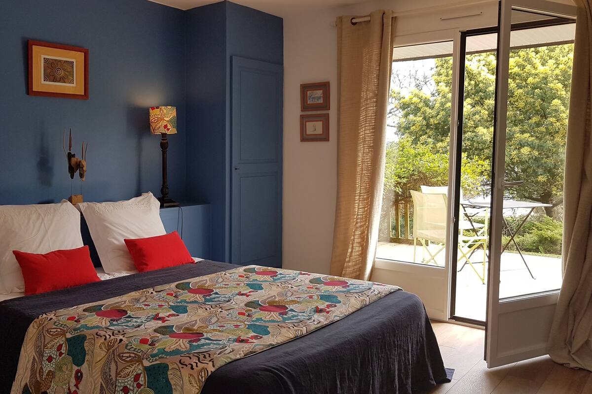 A bedroom with a large bed, two bedside lamps, a window with curtains, and a view of the outdoors.