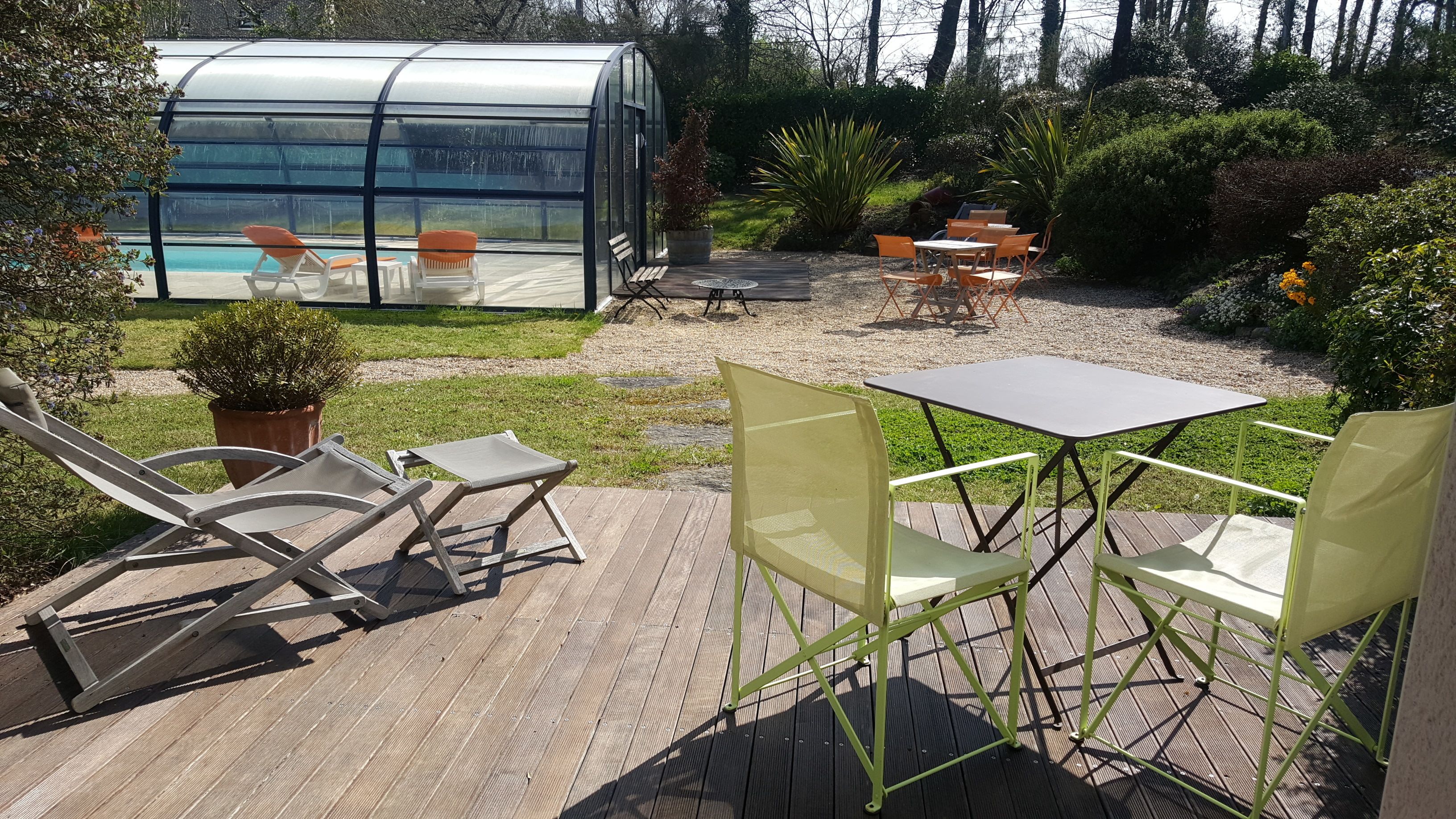 Un patio con mobiliario exterior, un invernadero de cristal y una piscina.