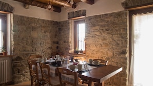 Un comedor rústico con pared de piedra, mesa y sillas de madera.