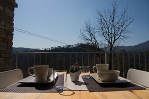 Mesa para dos con vistas a montañas y un árbol al fondo.