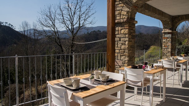 Una terraza con mesas y sillas que da a un paisaje montañoso.
