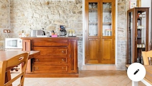 Una cocina con pared de piedra, armarios de madera, una cafetera y un microondas.