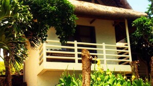 A traditional thatched-roof house with a stone staircase leading to a white balcony. - Alta Vista Ilocandia (Pagudpud)
