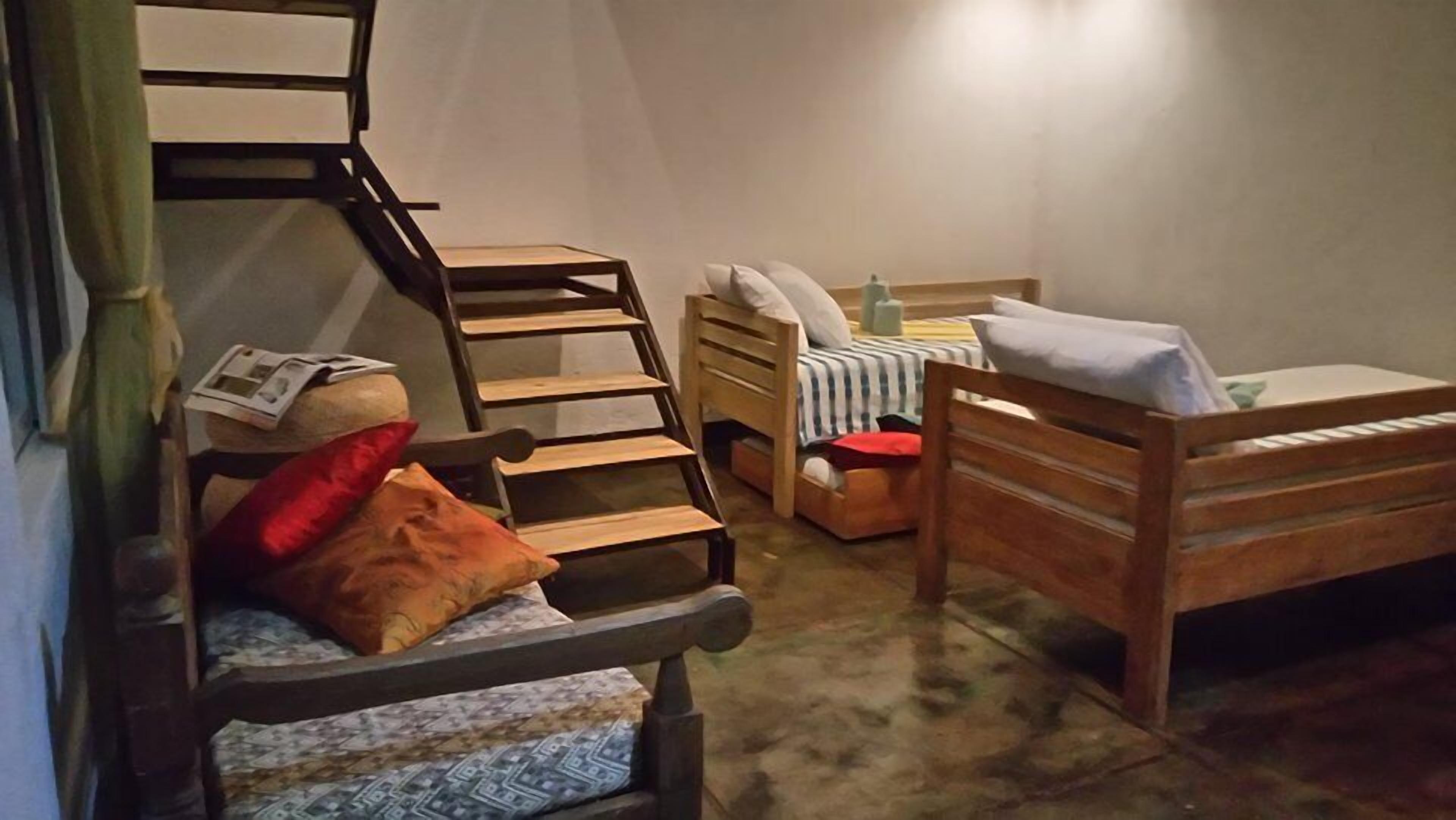 Una habitación compacta con una cama de madera, una mesita de noche pequeña, una silla y una escalera.